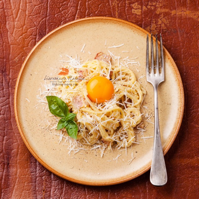 Pasta Carbonara with parmesan and yolk on textured background